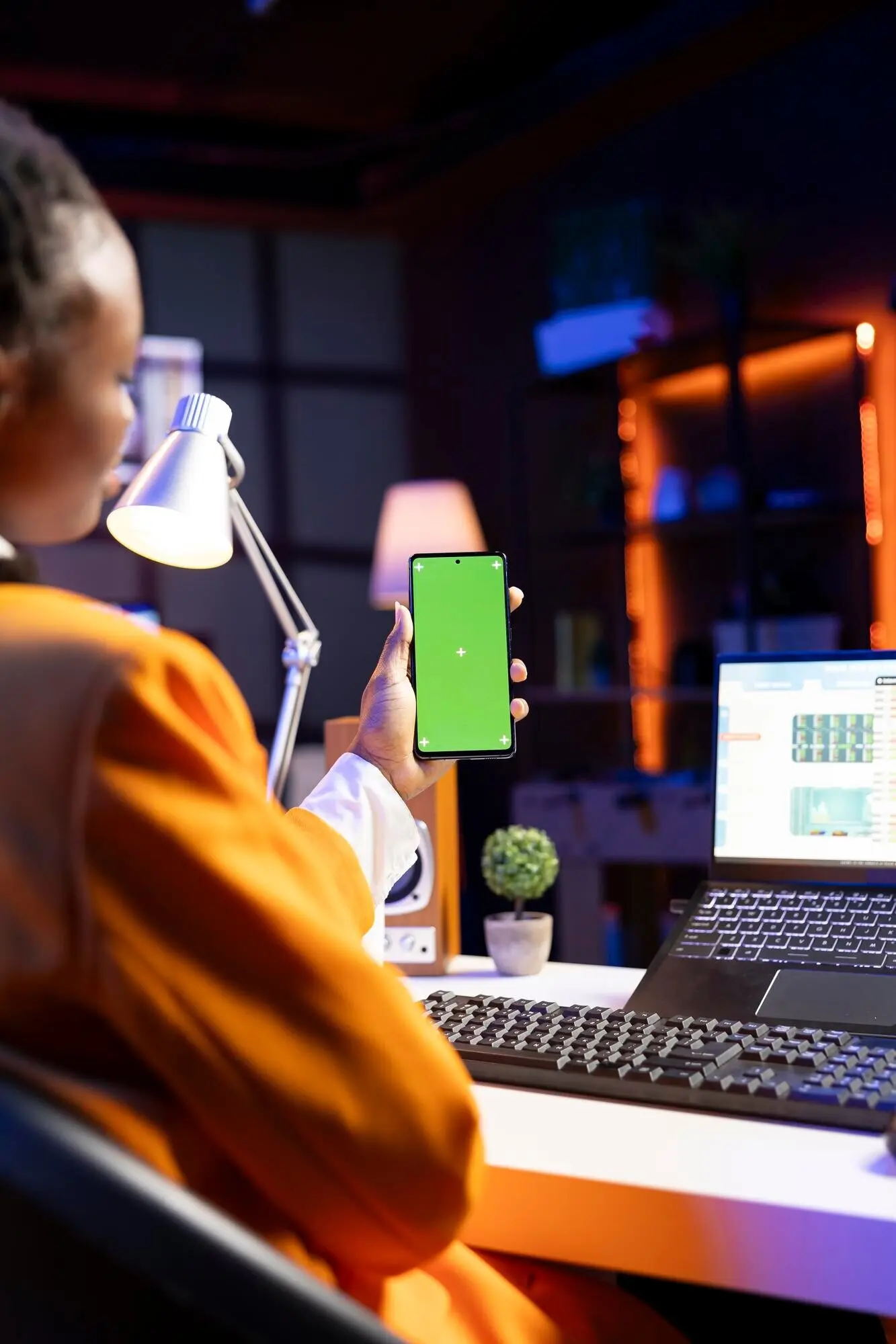 Женщина делает перерыв в проверке биржевых котировок, чтобы посмотреть видео на смартфоне с зеленым экраном.